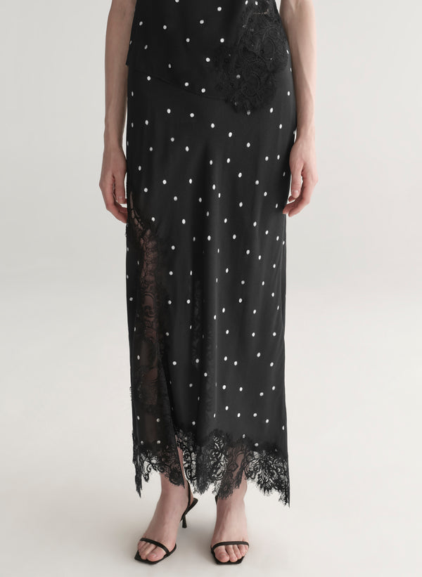woman wearing black satin and lace polka dot top and matching midi skirt