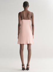 Woman wearing a light pink dress with feather details on a white background