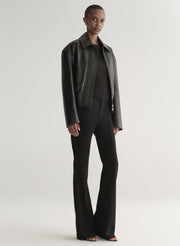 Person wearing a black leather jacket on a plain background