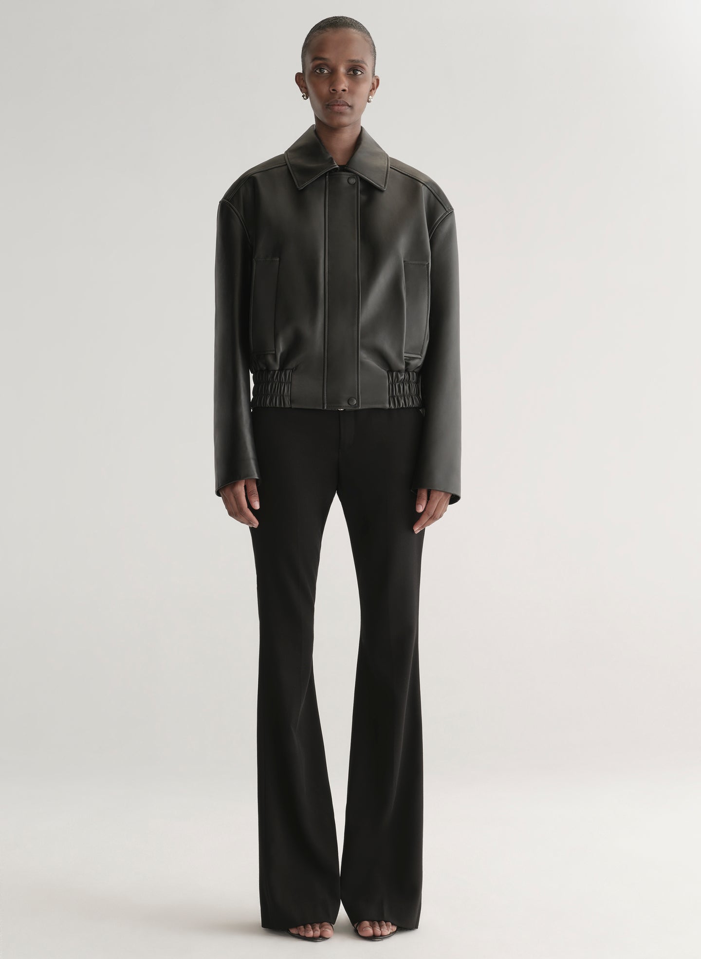 Person wearing a black leather jacket on a plain background