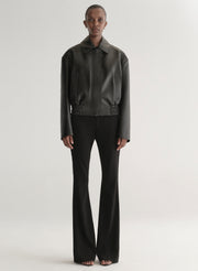 Person wearing a black leather jacket on a plain background