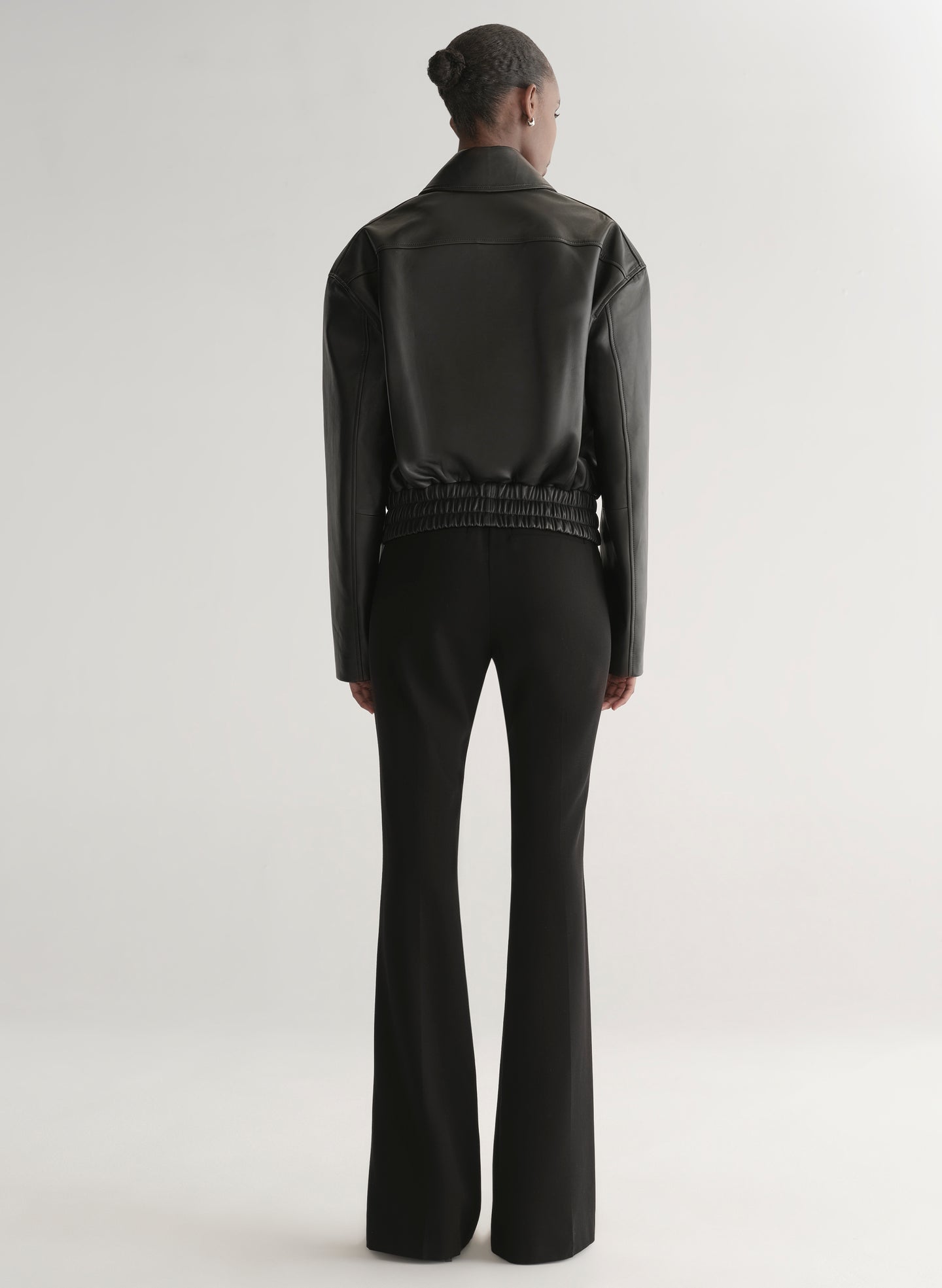 Person wearing a black leather jacket on a plain background