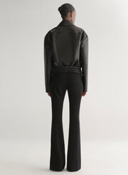 Person wearing a black leather jacket on a plain background