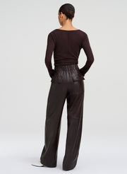 A model shown from the back wearing a dark brown long-sleeve top and matching wide-leg leather trousers, set against a plain light gray studio background.