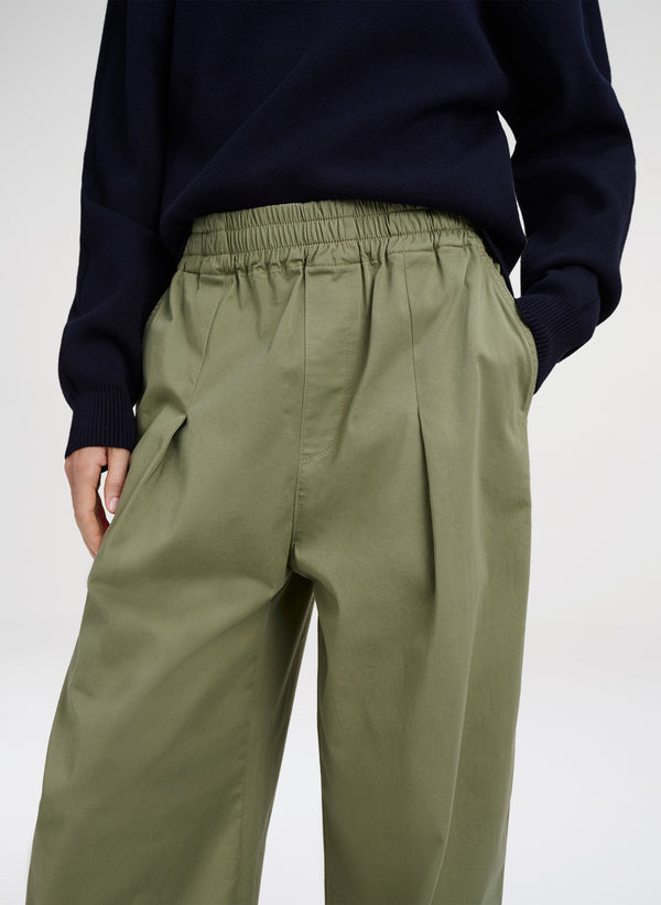 Person wearing olive green pants and a navy sweater on a white background