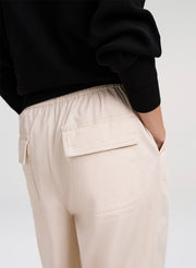 Person wearing beige cargo pants with a black sweater on a white background