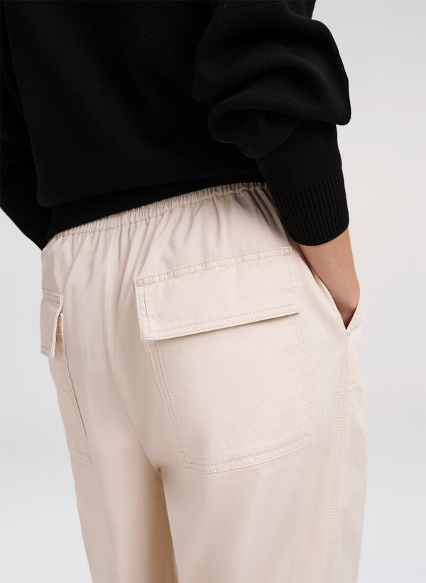Person wearing beige cargo pants with a black sweater on a white background