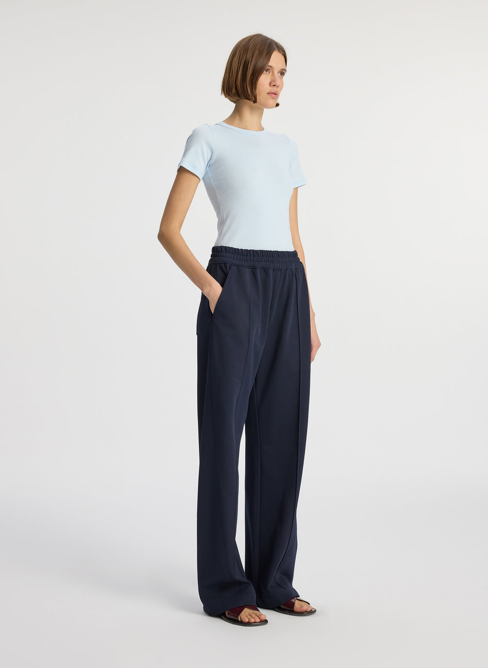side view of woman wearing light blue tshirt and navy blue pants