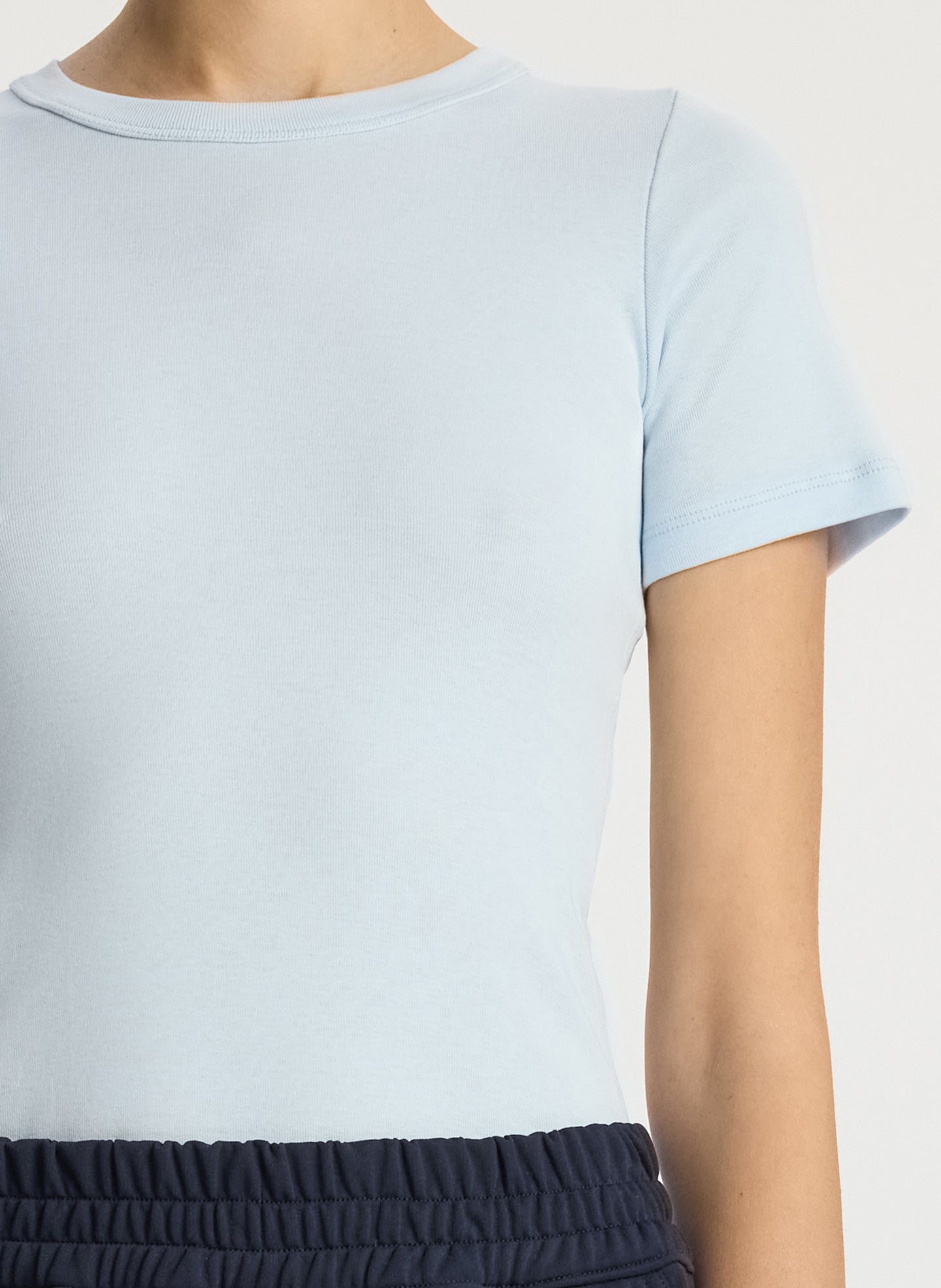 detail view of woman wearing light blue tshirt and navy blue pants