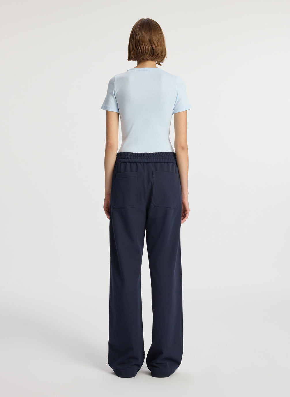 back view of woman wearing light blue tshirt and navy blue pants