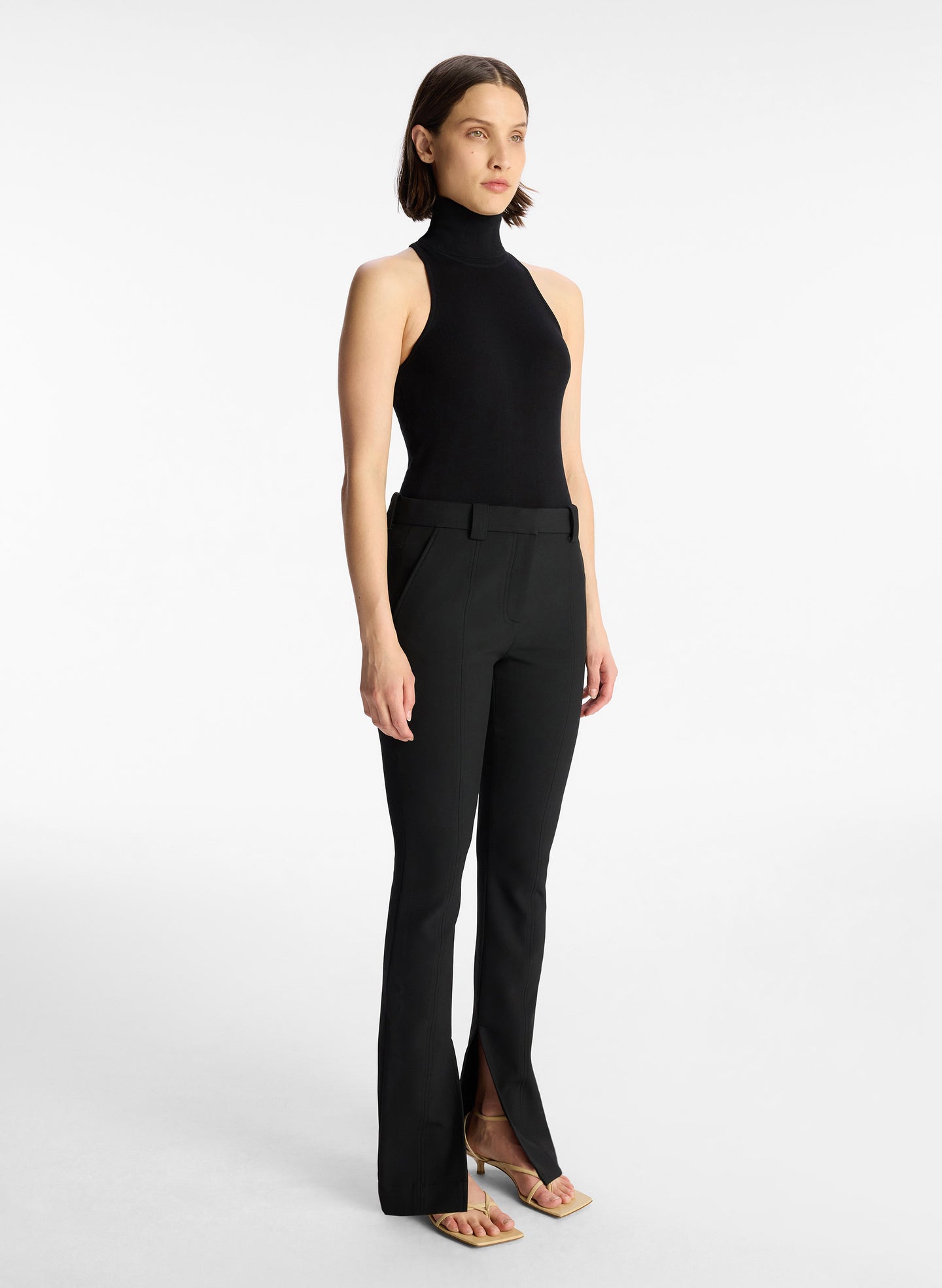 side view of woman wearing black sleeveless turtleneck top and black pants