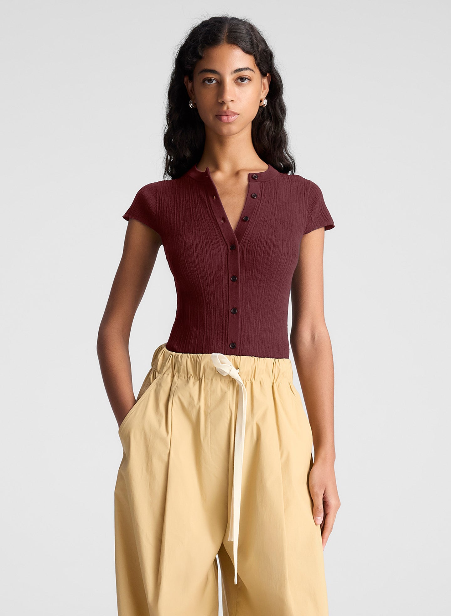 woman wearing burgundy short sleeve fine gauge knit cardigan with tan wide leg pants
