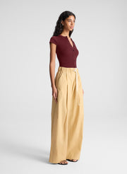 woman wearing burgundy short sleeve fine gauge knit cardigan with tan wide leg pants