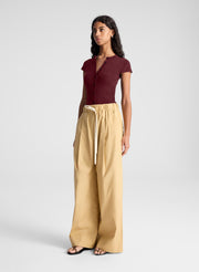 woman wearing burgundy short sleeve fine gauge knit cardigan with tan wide leg pants