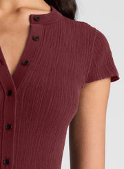 woman wearing burgundy short sleeve fine gauge knit cardigan with tan wide leg pants