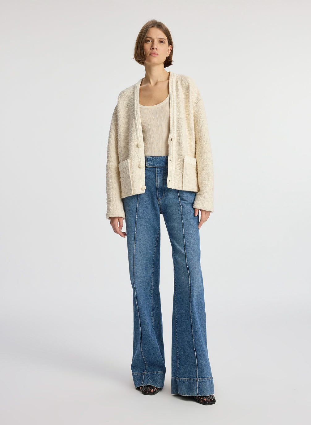 front view of woman wearing cream boucle jacket, cream tank top and medium blue denim jeans