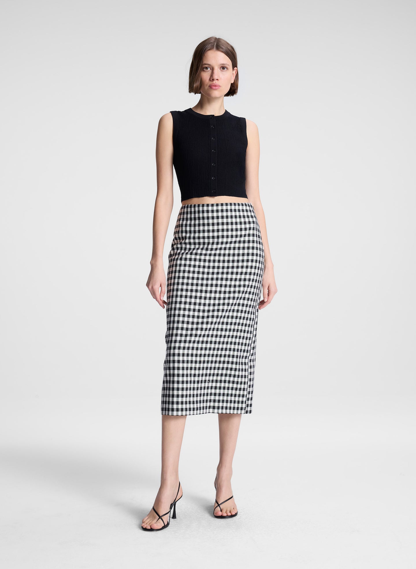 woman wearing black top and black and white gingham midi skirt