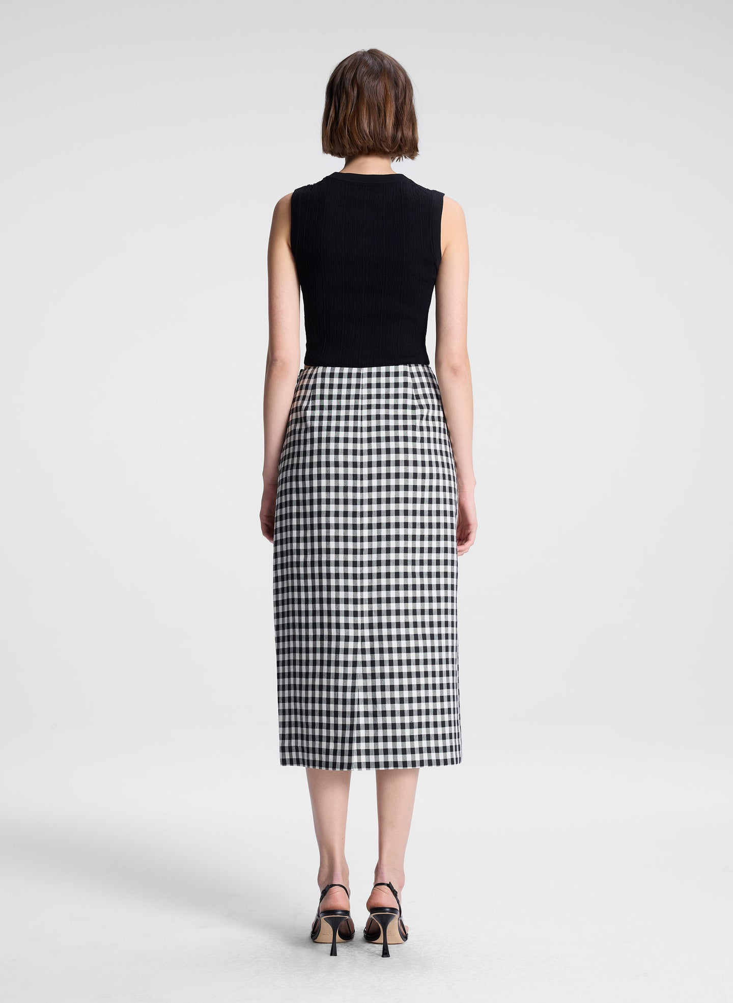 woman wearing black top and black and white gingham midi skirt