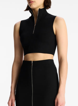 detail view of woman wearing black half zip compact knit sleevless cropped top with matching black skirt