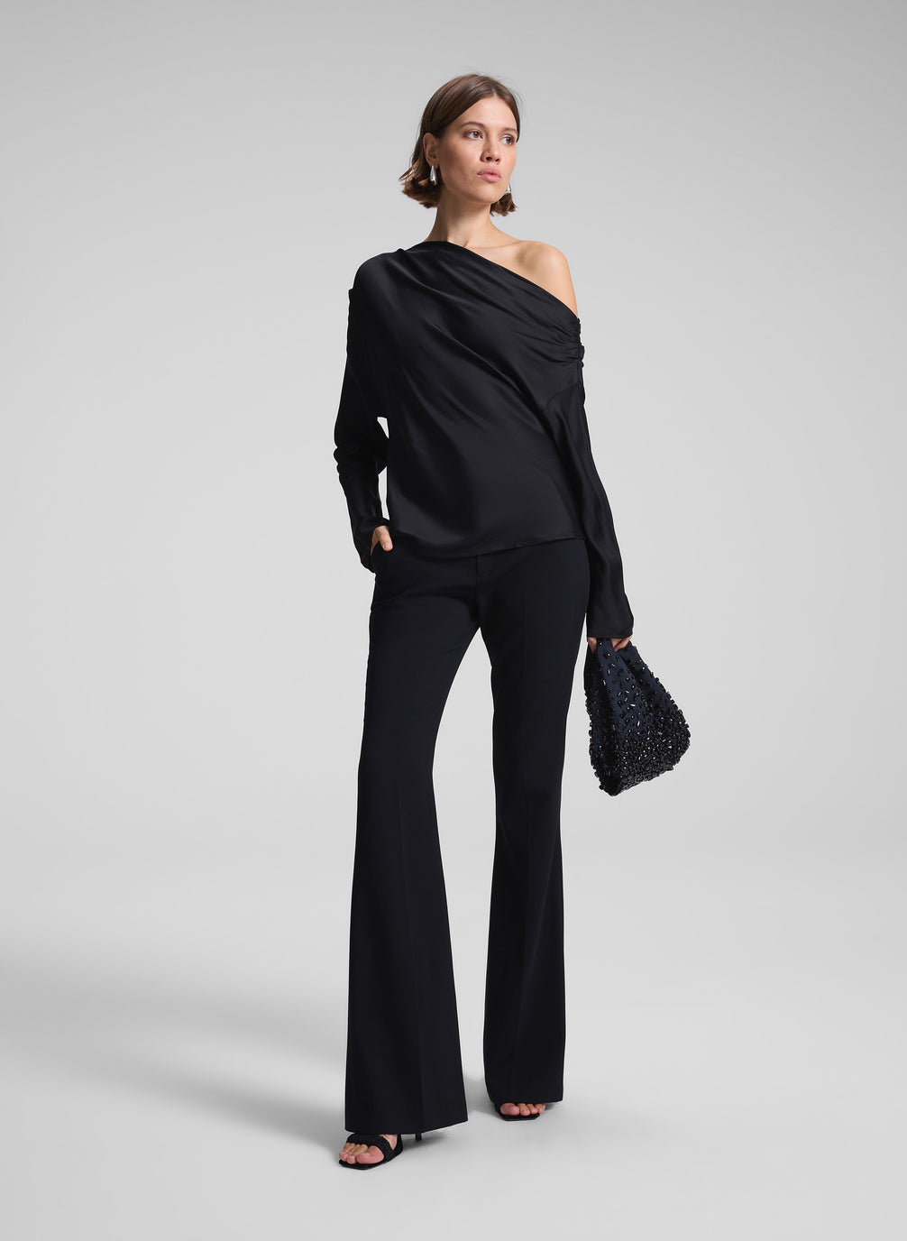 woman wearing black satin one shoulder top and black pants