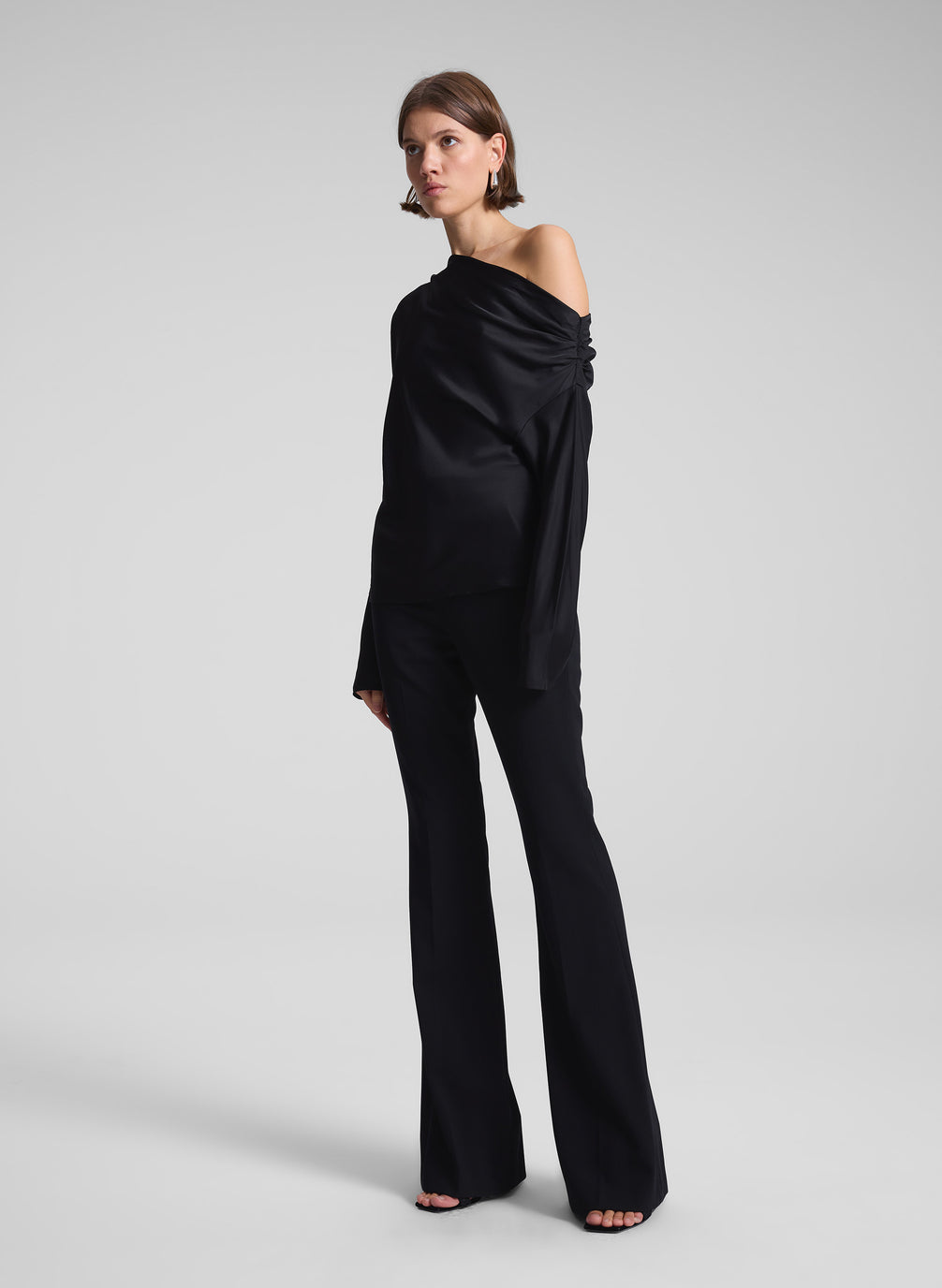 woman wearing black satin one shoulder top and black pants