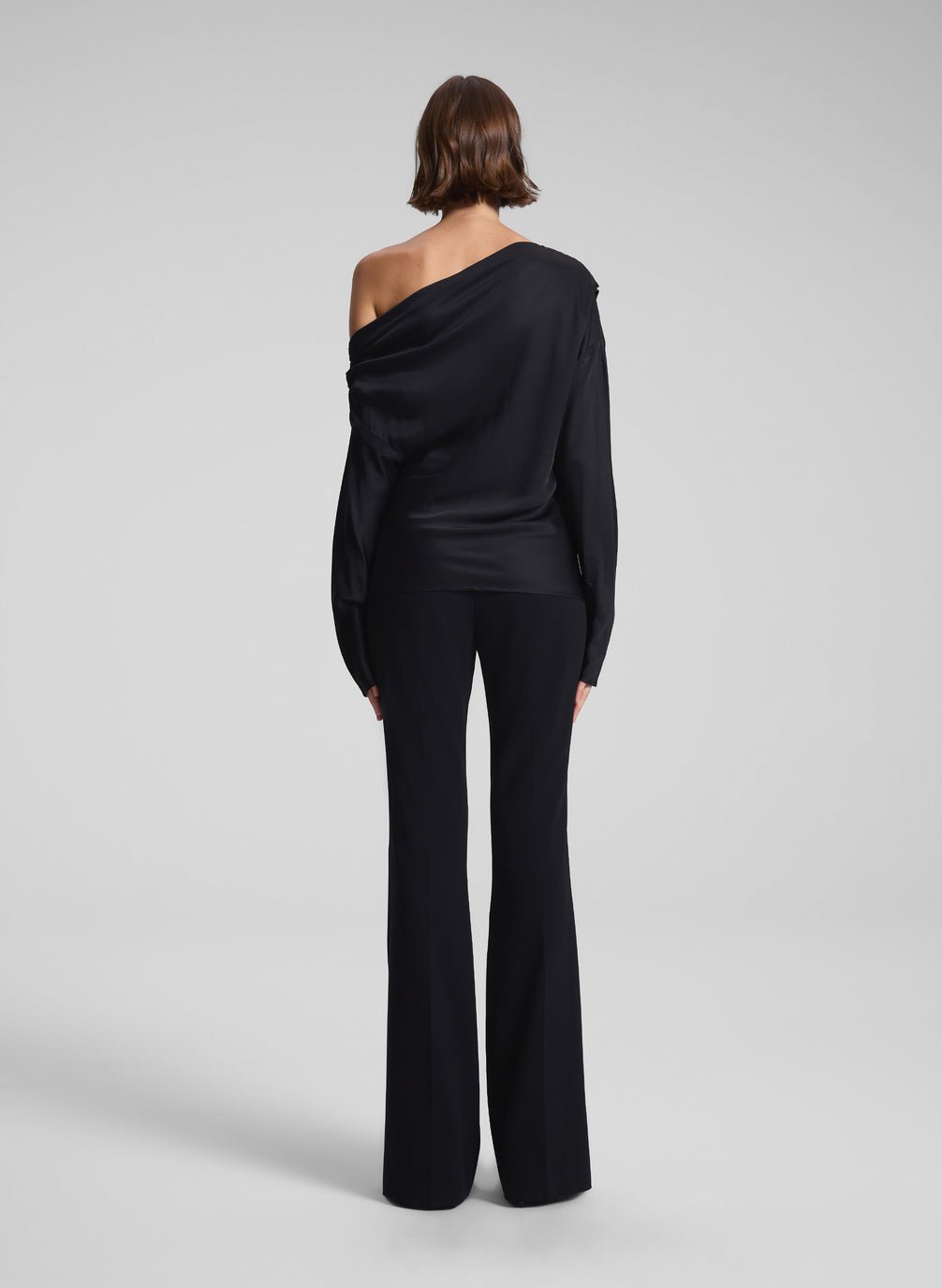 woman wearing black satin one shoulder top and black pants