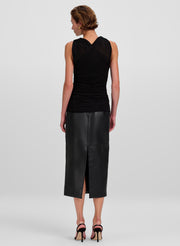 A woman shown from the back wearing a black sleeveless ruched top and a black leather midi skirt with a slit, paired with black high-heeled sandals, against a light gray studio background.