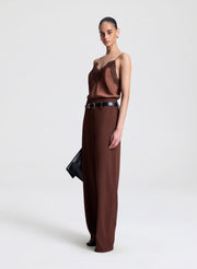 Woman wearing a brown top with lace detail and matching pants on a light gray background