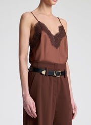 Woman wearing a brown top with lace detail and matching pants on a light gray background