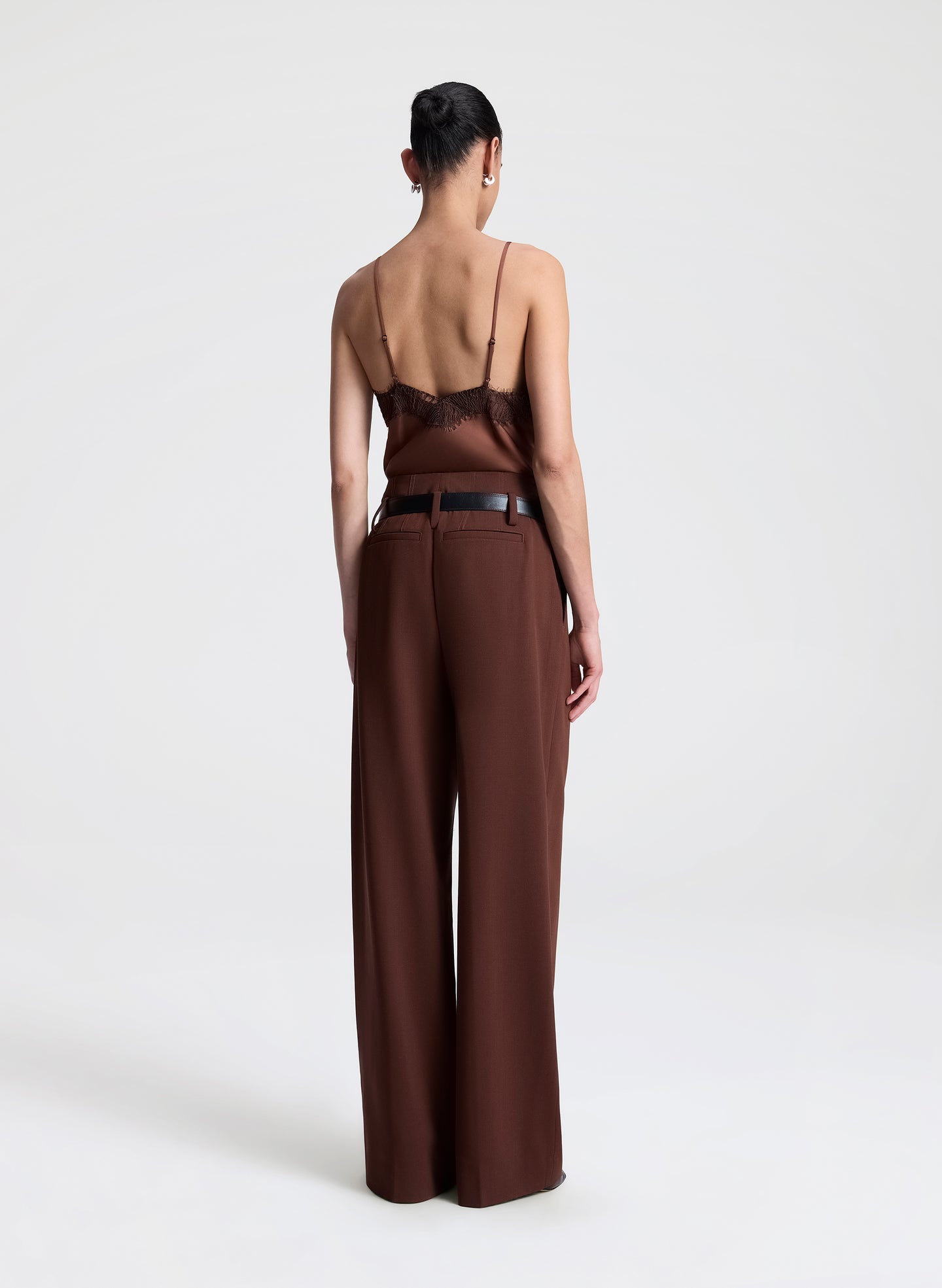 Woman wearing a brown top with lace detail and matching pants on a light gray background