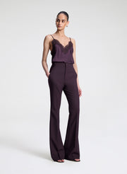 Woman wearing a dark purple lace-trimmed top and pants on a light gray background