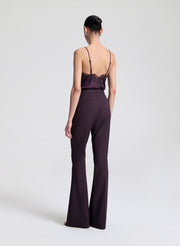 Woman wearing a dark purple lace-trimmed top and pants on a light gray background