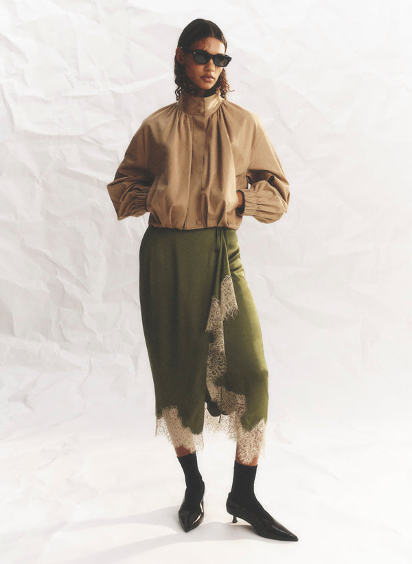 woman wearing green skirt and tan jacket