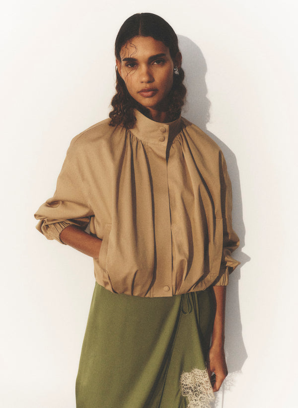 woman wearing tan jacket and green skirt