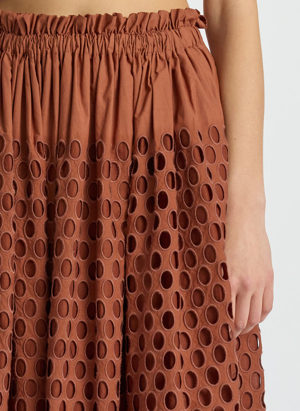 detail view of woman wearing brown sleeveless top and matching maxi skirt