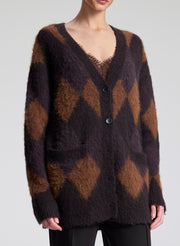 Person wearing a brown and black patterned cardigan on a white background