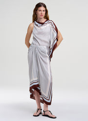 Woman wearing a sleeveless top with matching midi skirt with a pattern on a white background