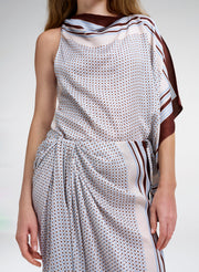 Woman wearing a patterned outfit with a scarf top on a plain background