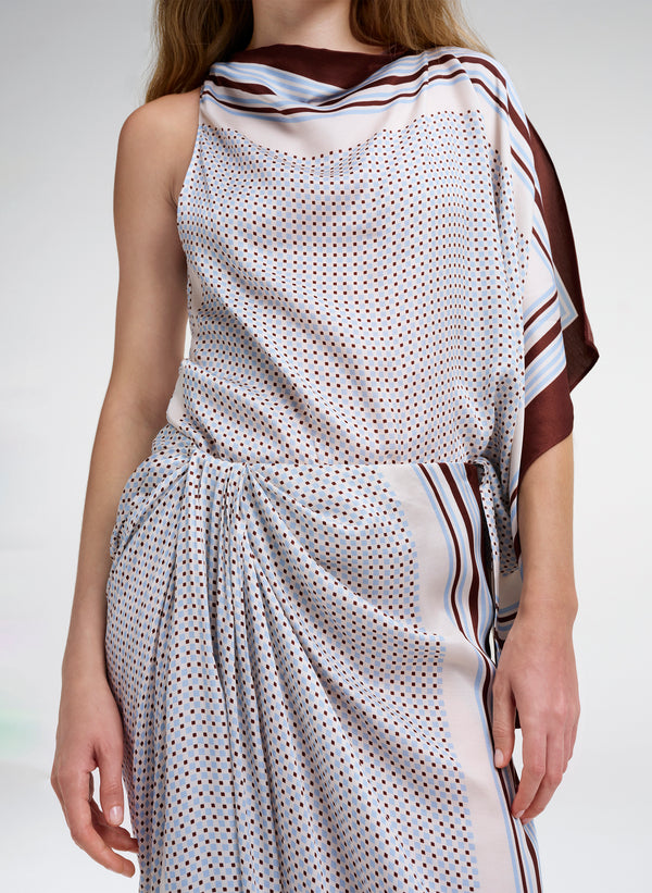 Woman wearing a patterned outfit with a scarf top on a plain background