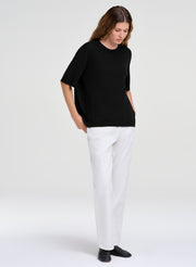 woman in black fine merino top and white denim jeans