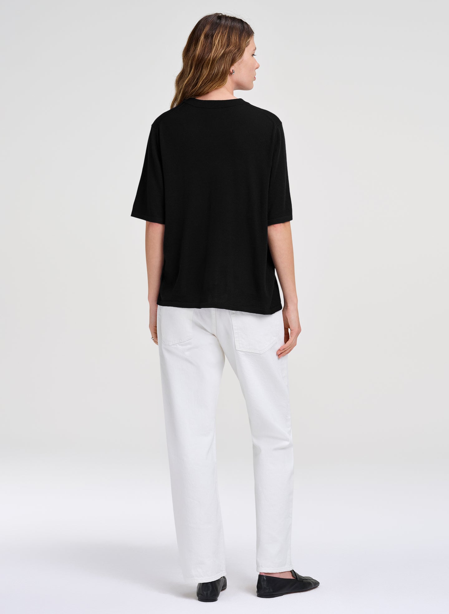 woman in black merino top and white jeans