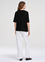 woman in black merino top and white jeans