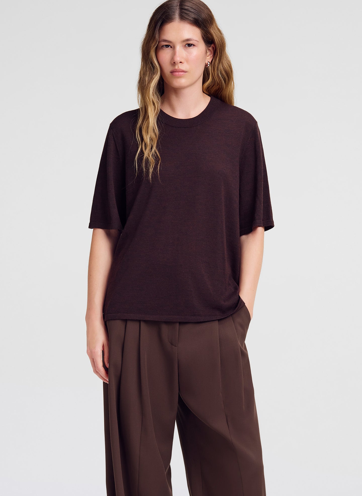 woman wearing brown merino short sleeve top and brown pleated pants