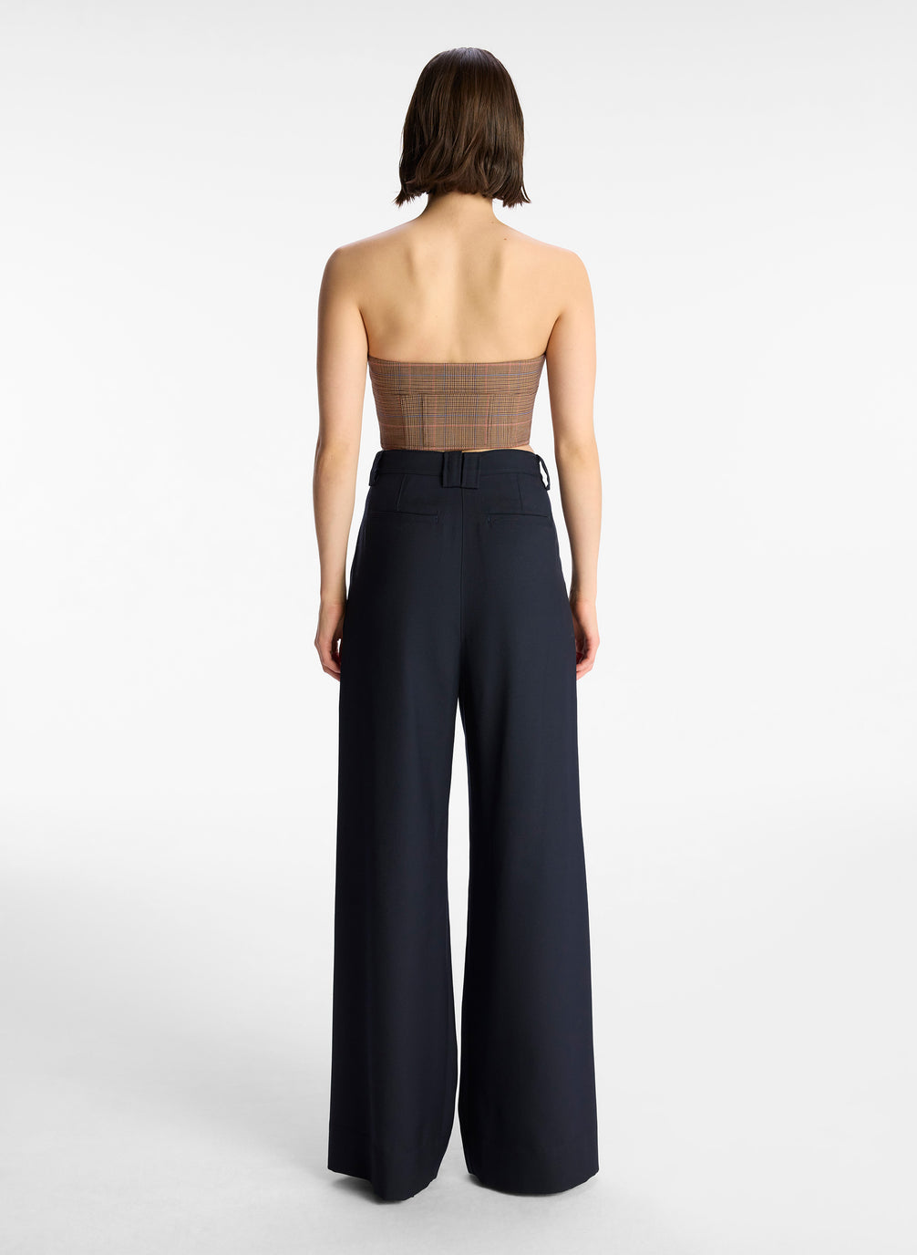 back view of woman wearing brown plaid strapless top and black pants