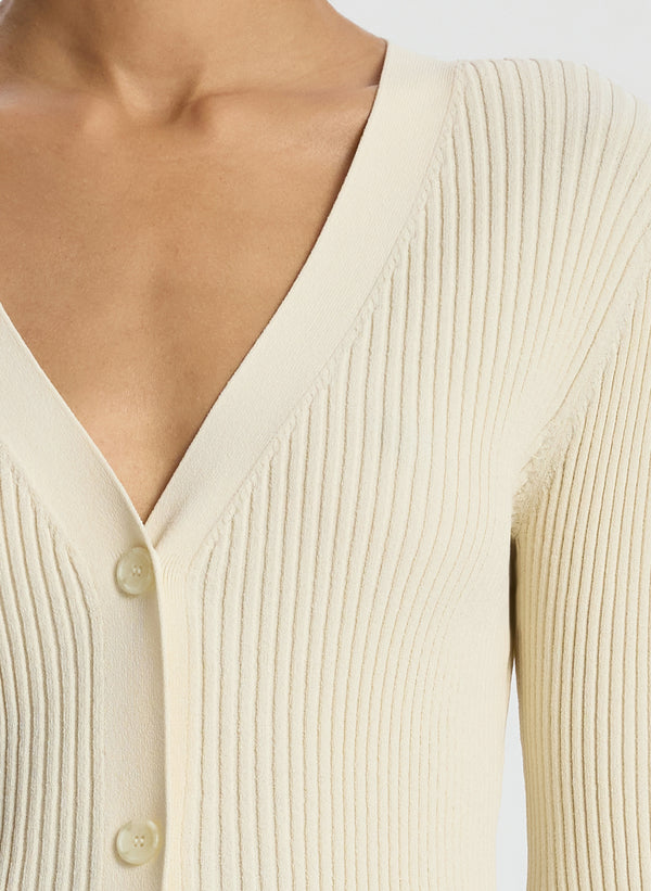 detail view of woman wearing cream cardigan and beige pants