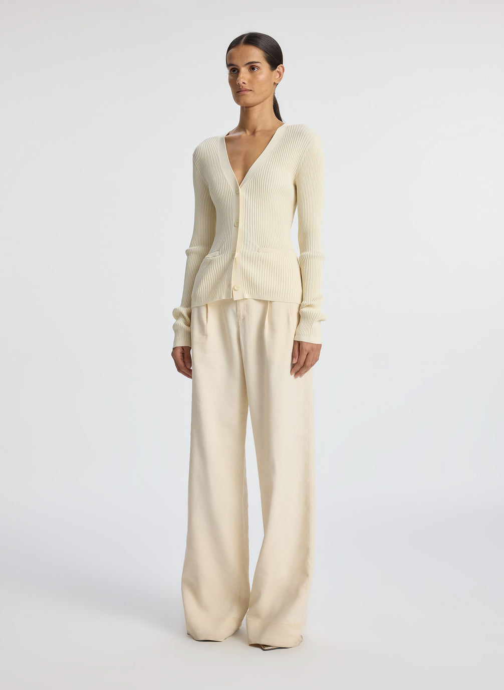 side view of woman wearing cream cardigan and beige pants