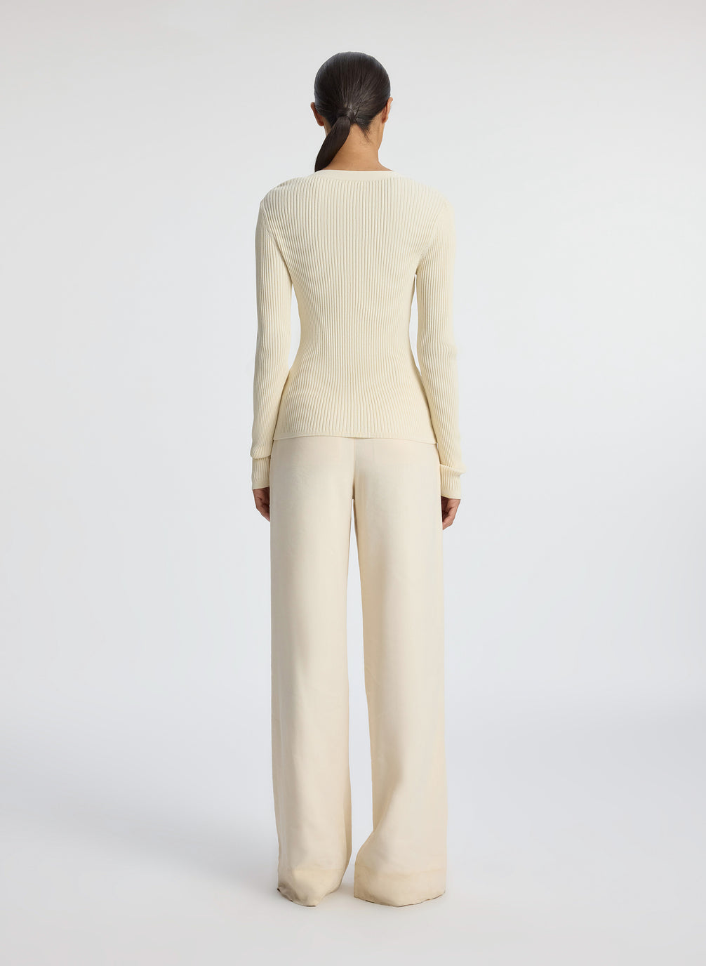 back view of woman wearing cream cardigan and beige pants