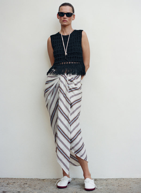 Person wearing a black sleeveless top and striped skirt against a white background