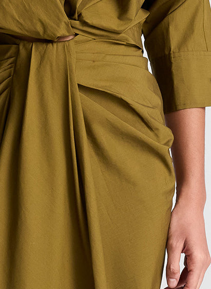 woman wearing olive green shirt and matching draped olive green midi skirt