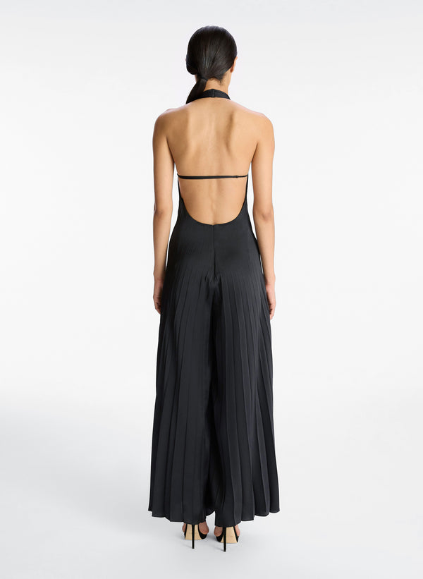 back view of woman wearing black satin pleated halter jumpsuit